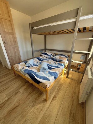 Una cama litera con estructura de madera y una colcha estampada.