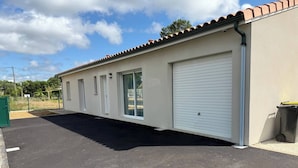 A building with a garage door, a drive-through window, and a paved driveway. - New home in the heart of the Médoc—4 bedrooms, garden, beaches 20 minutes away (Lesparre-Médoc)