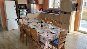 A compact kitchen with a dining area, equipped with a refrigerator, oven, and a window providing natural light. - New home in the heart of the Médoc—4 bedrooms, garden, beaches 20 minutes away (Lesparre-Médoc)