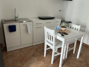Un angolo cottura attrezzato con lavello, piano di lavoro e zona pranzo con tavolo e sedie.