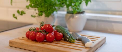 Une planche à découper en bois avec des tomates cerises et une courgette, posée sur un plan de travail de cuisine.