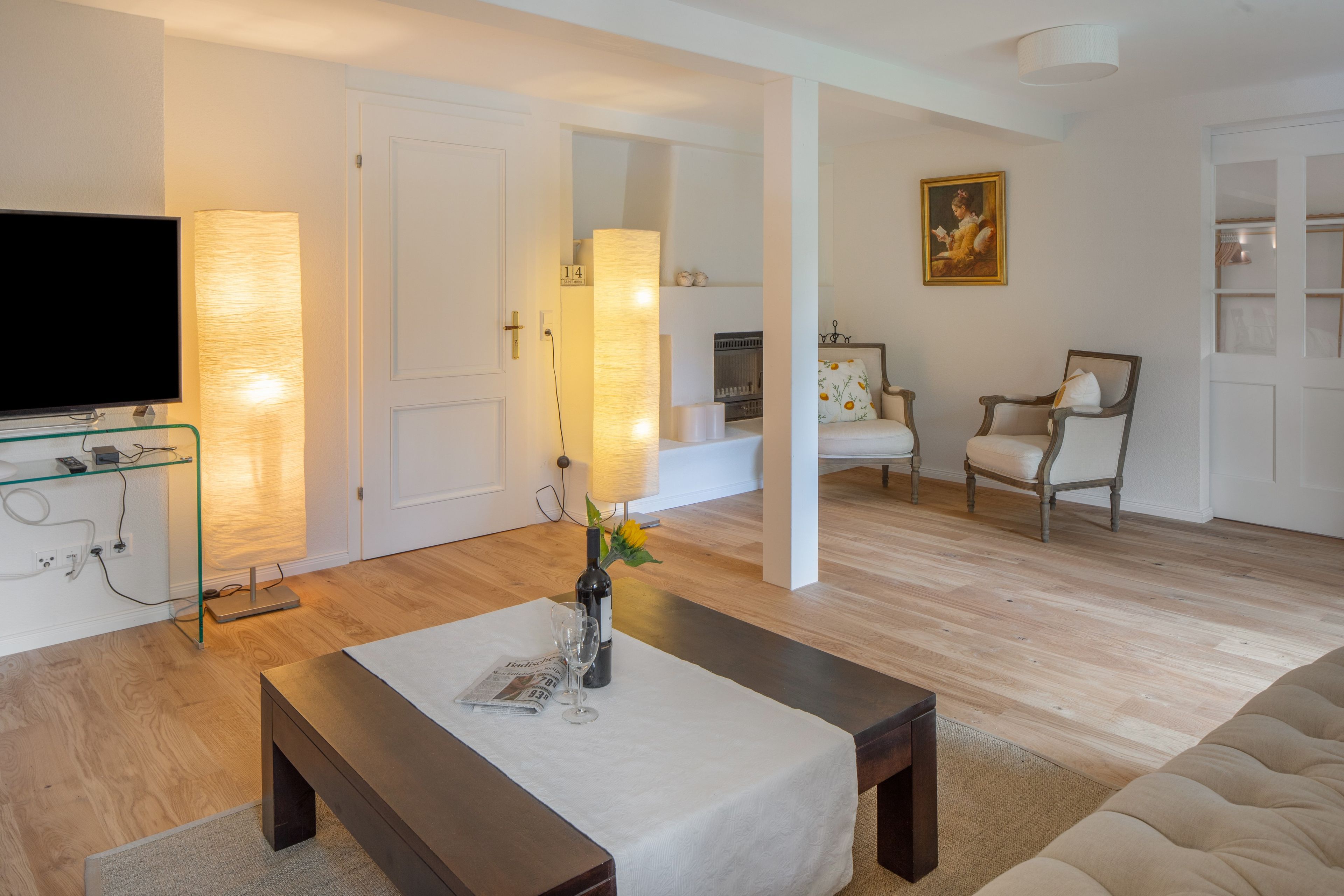 Ein modernes Wohnzimmer mit Flachbildfernseher, Glastisch, Sofa und Kamin.