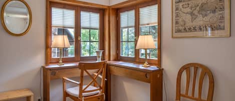 Une pièce d’angle avec un bureau en bois, deux chaises, un miroir et une carte encadrée accrochée au mur.