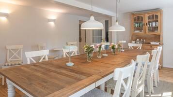 Ein Essbereich mit Holztisch, weißen Stühlen und Pendelleuchten.