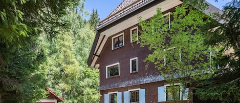 Un edificio de dos pisos con fachada de ladrillo, múltiples ventanas y techo inclinado.