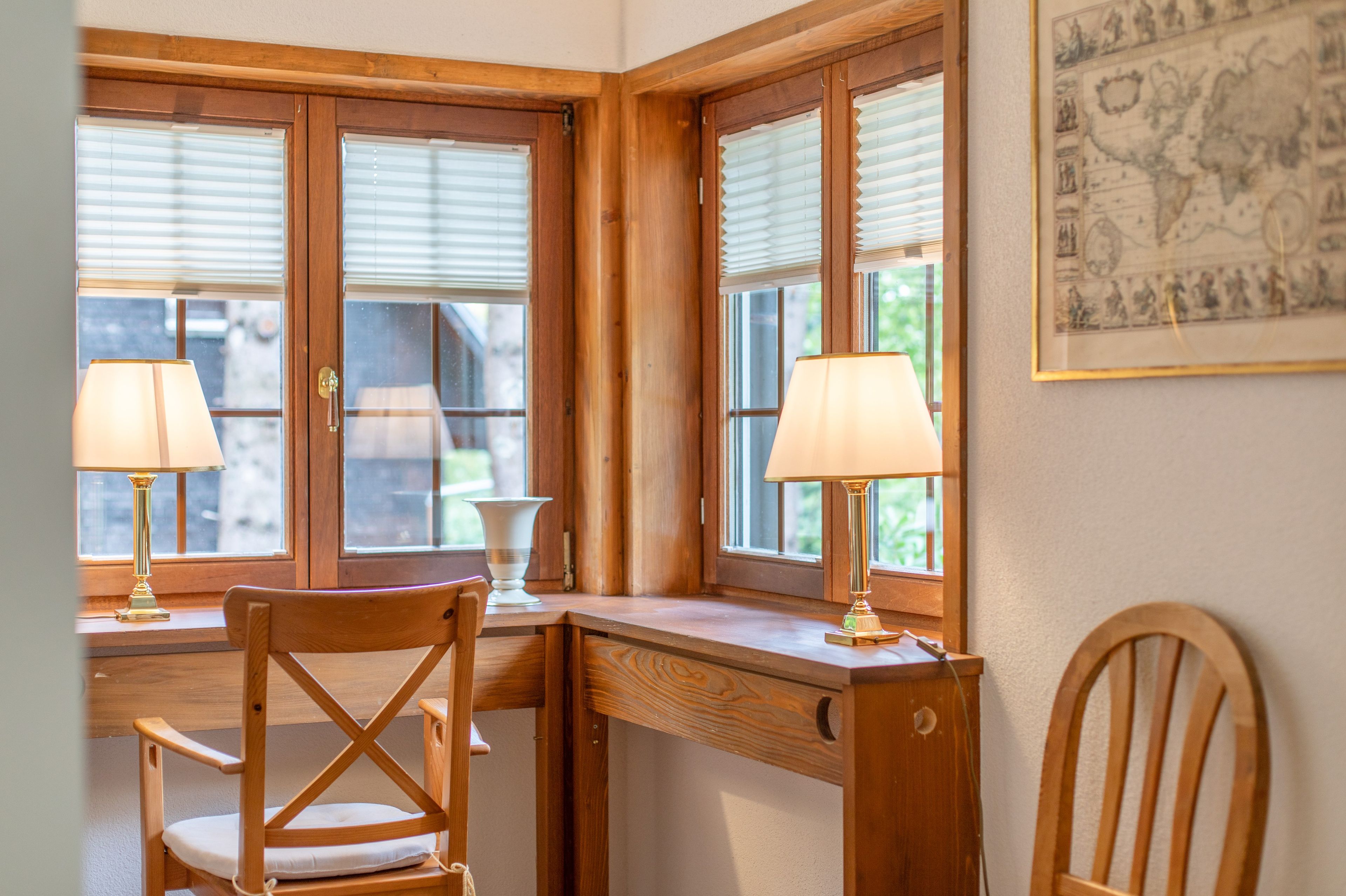 Une pièce d’angle avec un bureau en bois, deux chaises et deux lampes.