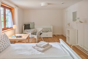 Ein Schlafzimmer mit Bett, Sessel, Schreibtisch und Fenster.