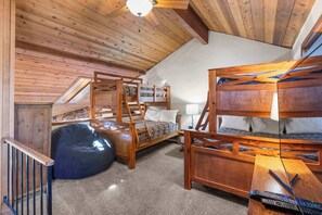 Une pièce confortable avec un lit superposé, un fauteuil poire et un bureau avec une lampe.