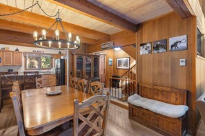 A wooden interior with a dining area, kitchen, and a bench with a cushion. - 2BR + Loft Condo | Shared Pool & Shuttle Access (Mammoth Lakes)