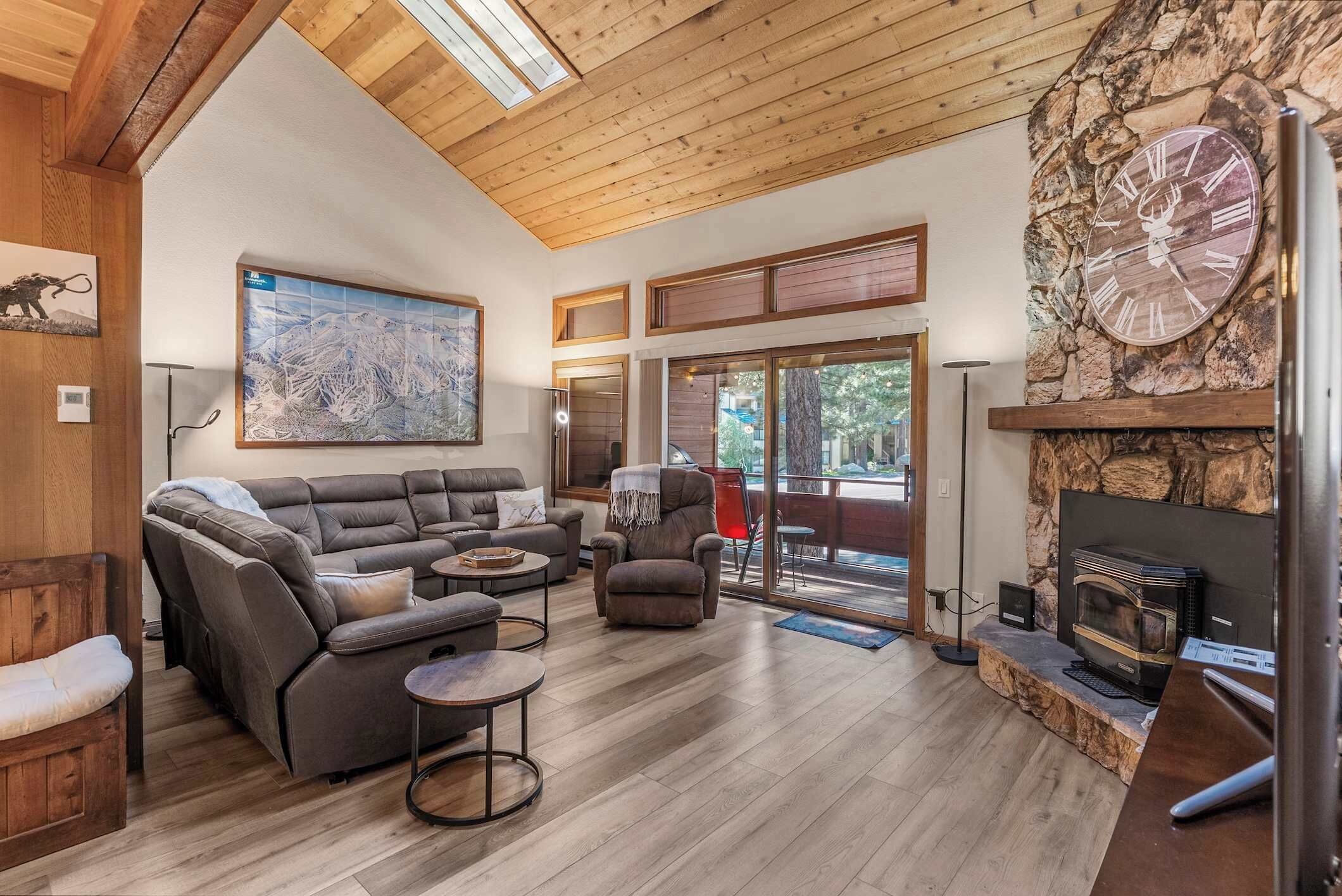 A spacious living room with a sectional sofa, a fireplace, and a large window.
