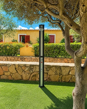 A stone wall with a metal post in a landscaped area. - GioYa House – Three-room apartment with a garden, 100 meters from Pittulongu Beach (Pittulongu)