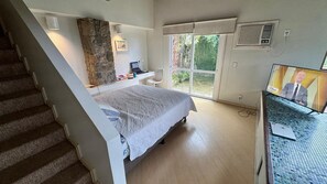 Een slaapkamer met een bed, een bureau, een televisie en een trap.