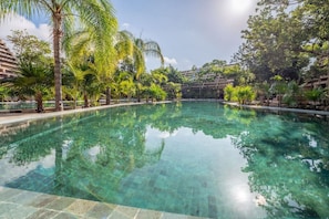 Ein klares Schwimmbecken, umgeben von üppiger Vegetation und moderner Architektur.