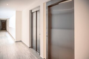 Un couloir avec deux ascenseurs et un plancher en bois.