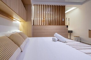 A modern hotel room with a large bed, wooden headboard, and a view through a wooden slat partition. - Luxury 1 BR | Gym, Rooftop Pool & Lounge w/Parking (Playa del Carmen)
