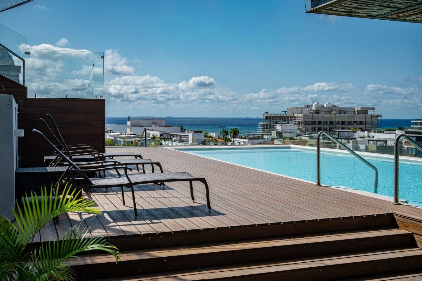 Ein Pool auf dem Dach mit Liegestühlen und Blick auf den Ozean und die Gebäude.