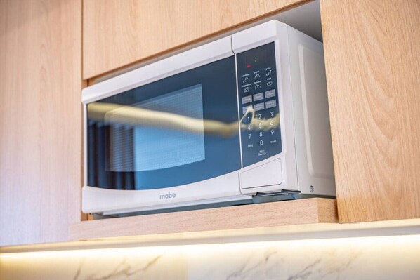 A microwave oven with a digital control panel, housed in a wooden cabinet. - Luxury 1 BR | Gym, Rooftop Pool & Lounge w/Parking (Playa del Carmen)