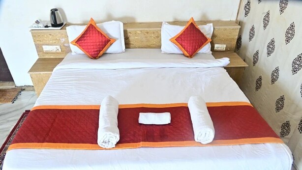 Habitación de hotel con cama, dos almohadas, mesita de noche y pared con diseño.