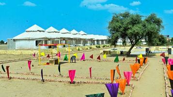 A series of white tents with a clear sky and a tree in the background.