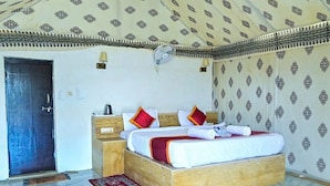 Ein Zimmer mit einem Bett, einem Nachttisch, einem Wandventilator und ornamentalem Wandpapier.