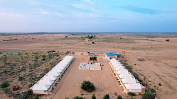 A large, open area with a central building surrounded by tents, set in a desert landscape.