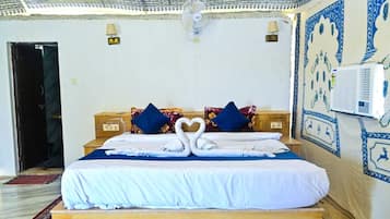 A hotel room with a bed, pillows, a wall-mounted air conditioner, and a patterned wall.