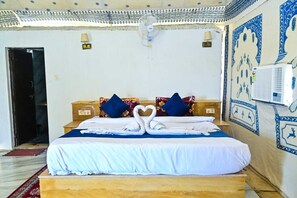 Habitación de hotel con cama, almohadas, aire acondicionado de pared y pared con diseño.