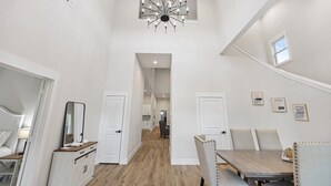 Ein modernes Interieur mit Essbereich, einem zur Küche führenden Flur und einer Treppe.