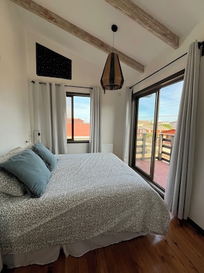 A bedroom with a bed, a hanging light fixture, a window, and a view of the outside. - Newly renovated house just a few steps from the beach and wetlands (La Laguna)