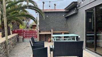 An outdoor patio with wicker furniture, a red picket fence, and a stone wall.