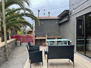 An outdoor patio with wicker furniture, a red picket fence, and a stone wall.