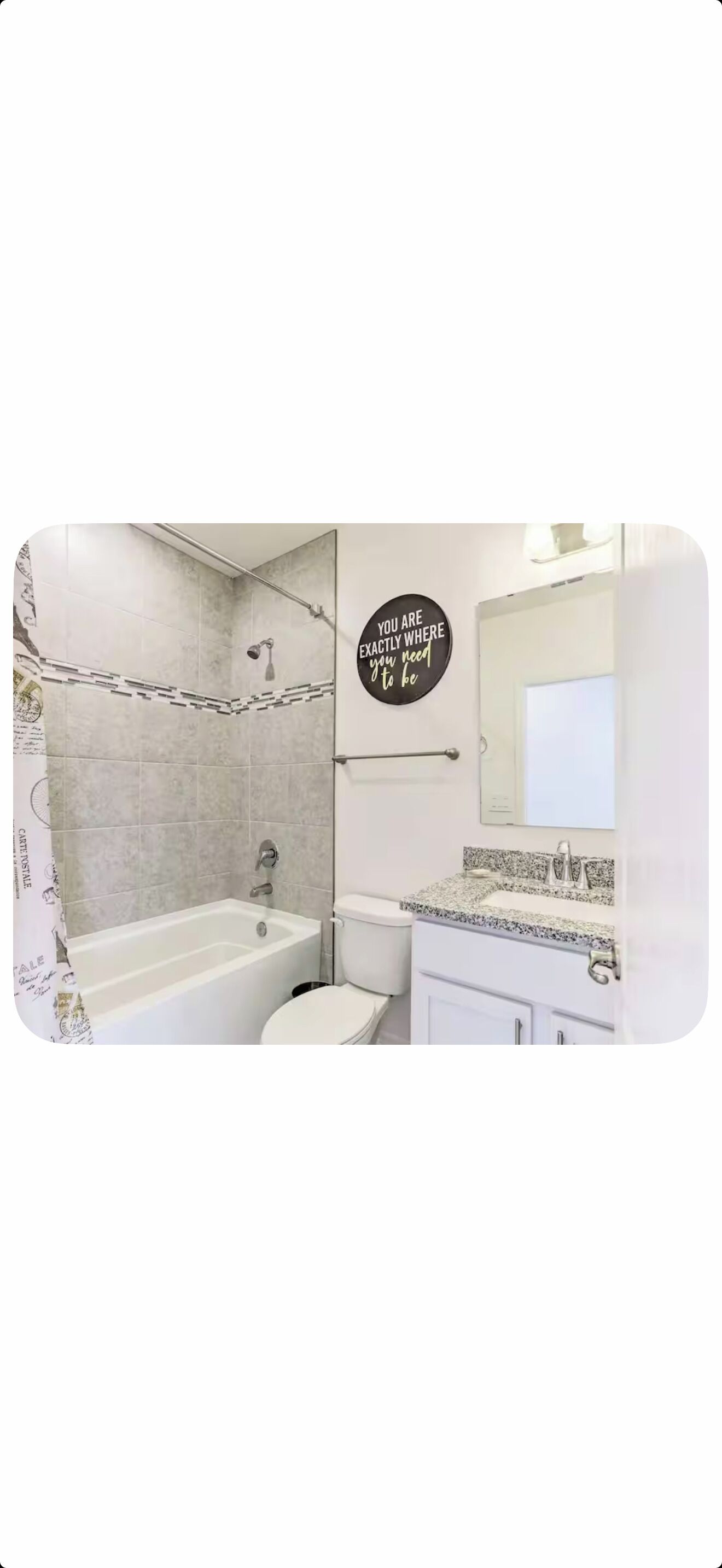 Een badkamer met een bad, toilet en wastafel. Op de muur staat een motiverende quote.