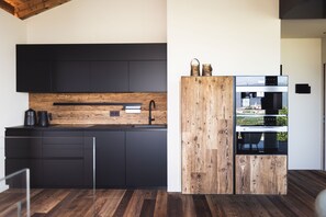 A modern kitchen with black cabinets, a wooden countertop, and a built-in oven.