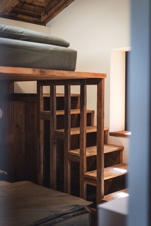 A wooden staircase with a mattress on the top landing.