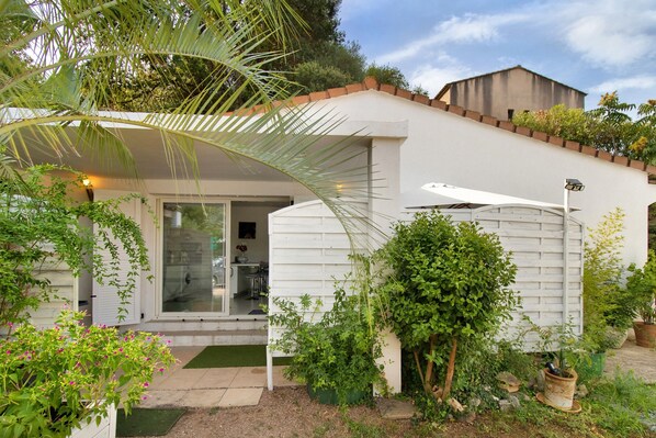 Une maison moderne dotée d’un patio couvert, d’une cuisine ouverte et d’une grande variété de plantes.