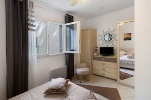 A bedroom with a bed, a dresser, a chair, a television, and a mirror. - Villa “Pavillon 1013” with Private Pool, Terrace & Wi-Fi (Bastelicaccia)