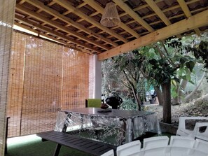 An outdoor patio area with a table and chairs, a woven ceiling, and a tree. - Villa “Pavillon 1013” with Private Pool, Terrace & Wi-Fi (Bastelicaccia)