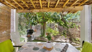 An outdoor patio with a table set for dining, surrounded by greenery and a brick wall.