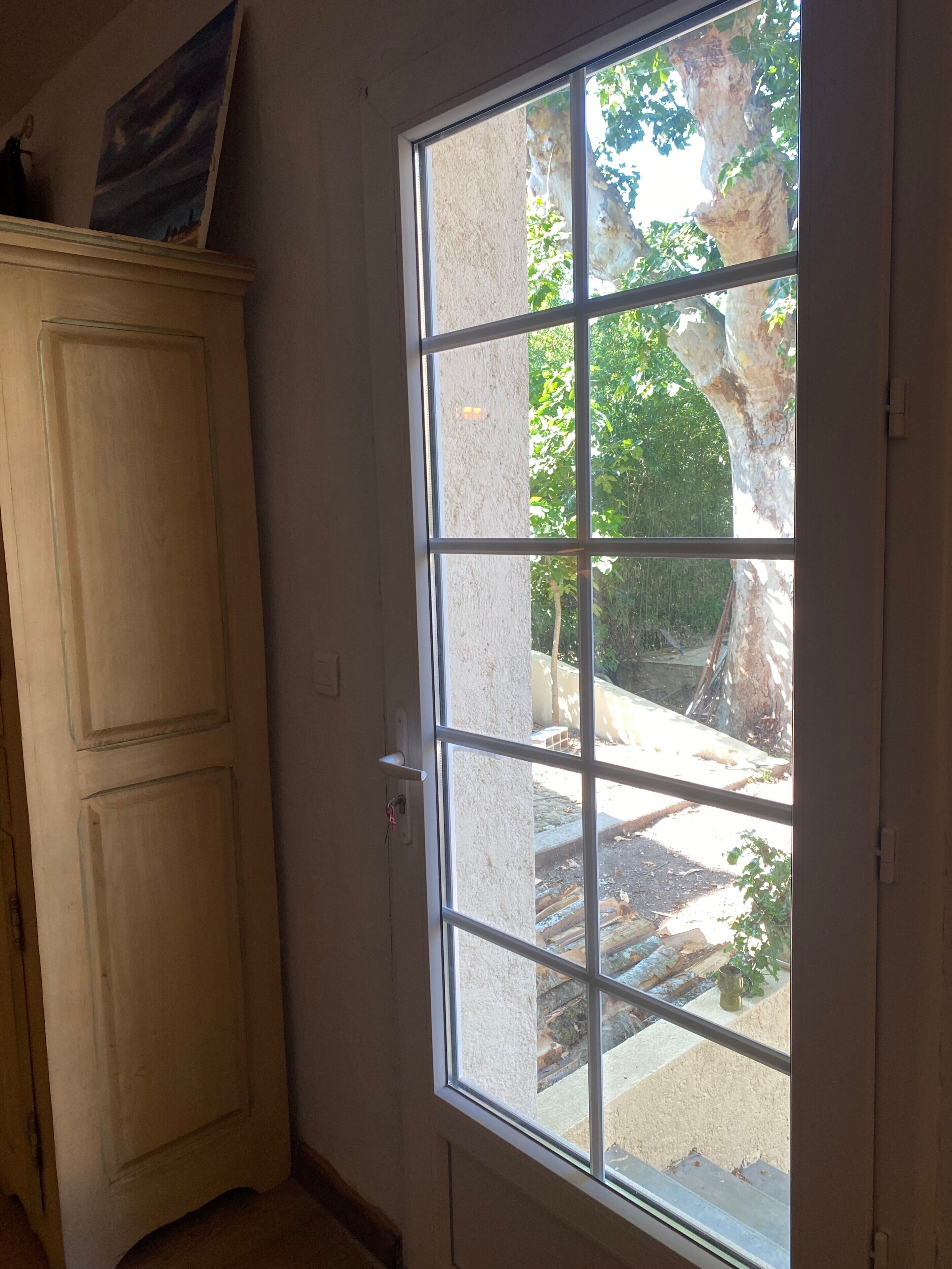 A room with a large window, a door, and a cabinet.