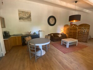 Un soggiorno con un tavolo rotondo, due sedie, un divano, un tavolino, una sveglia e una parete divisoria in legno.