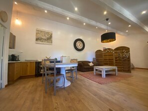 Un'ampia zona giorno con tavolo da pranzo, divano e pensile in legno.