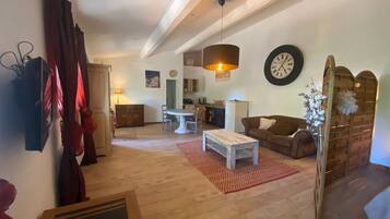 Un vaste salon doté d’un plancher en bois, d’une table à manger, d’un canapé et d’une cuisine à l’arrière-plan.