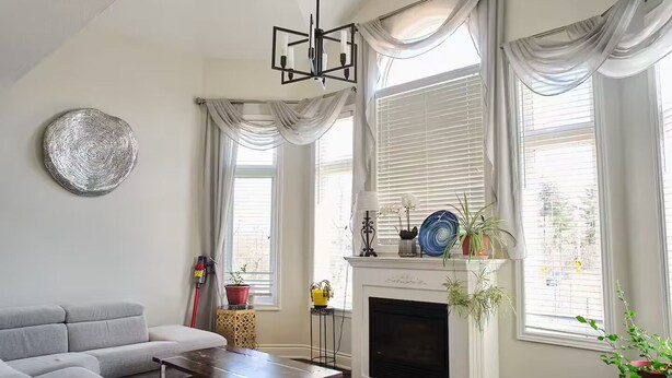 Sala de estar com lareira, janelas amplas com cortinas, um sofá e uma mesa de centro.