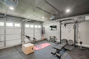 Ein Fitnessraum mit Trainingsgeräten, einer Holzbox und einer roten Matte.