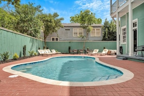 Piscina com espreguiçadeiras e um pátio de tijolos.