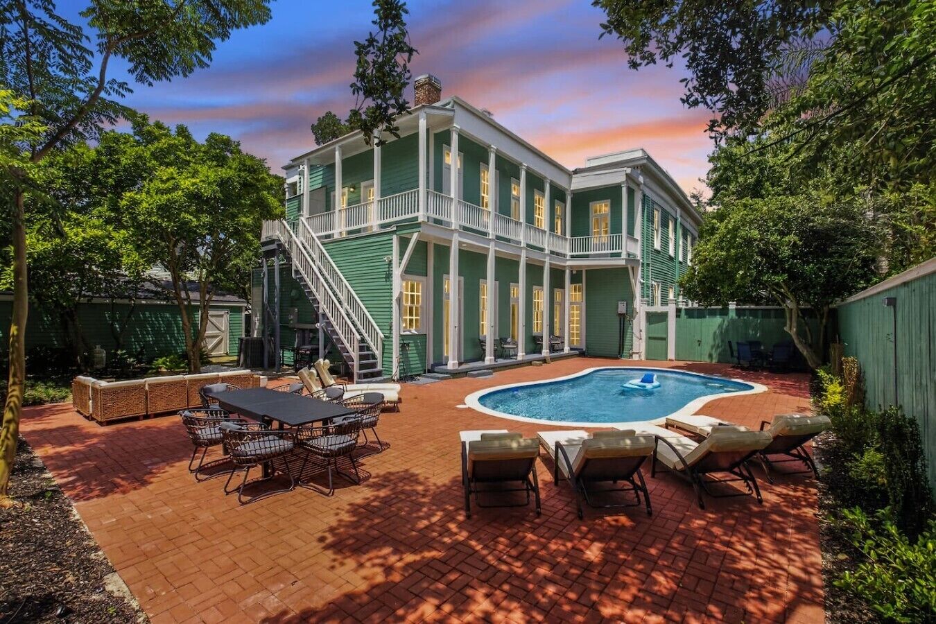 A two-story house with a swimming pool, outdoor seating, and a staircase leading to the upper floor.