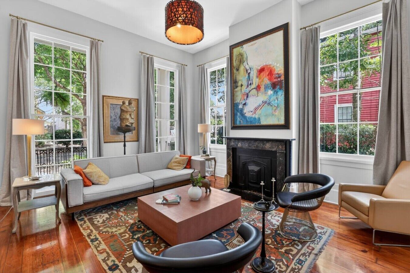 A spacious living room with a fireplace, large windows, and a colorful abstract painting.