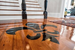 Un plancher en bois poli orné d’un grand motif abstrait aux couleurs sombres.