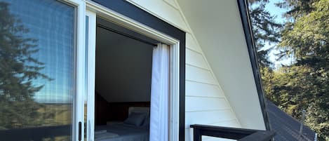 A bedroom with a bed, a window, and a door leading to an outdoor area.