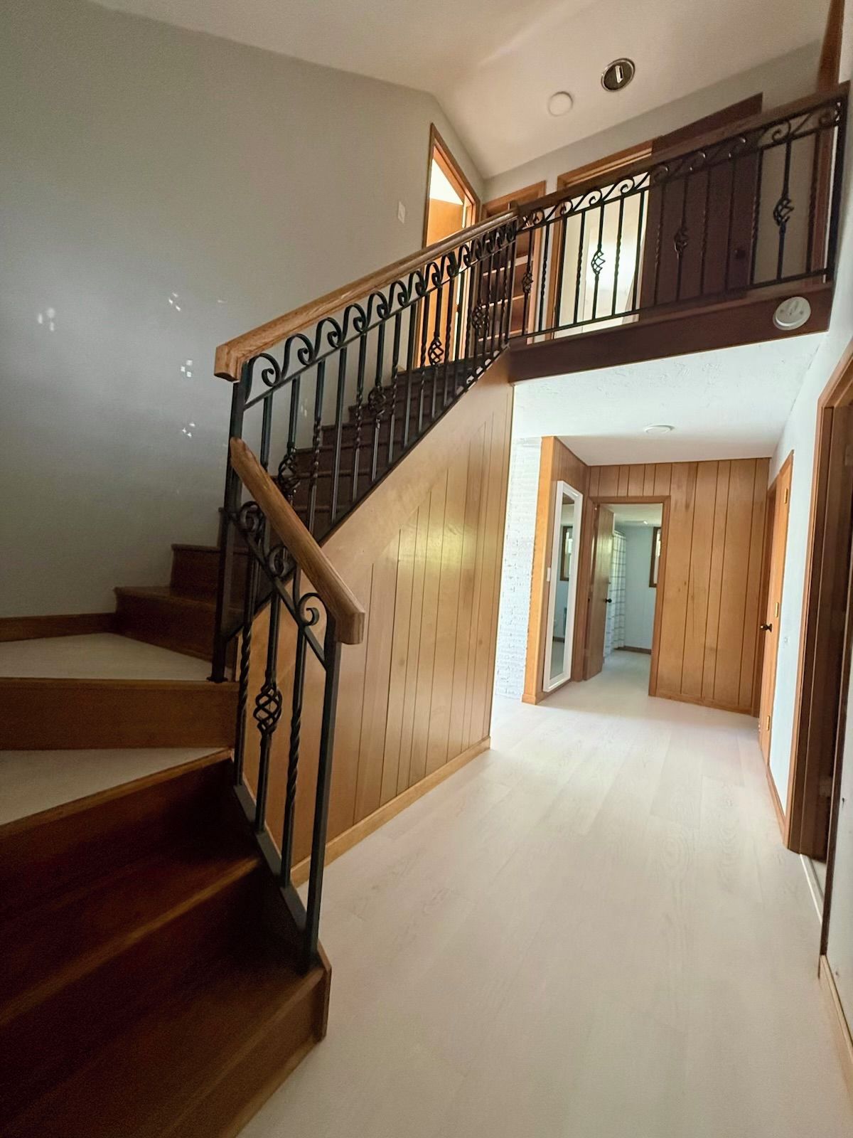 A wooden staircase with black metal railings leading to an upper floor.